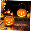 Two glowing orange pumpkin solar lanterns with jack-o'-lantern cutout faces
