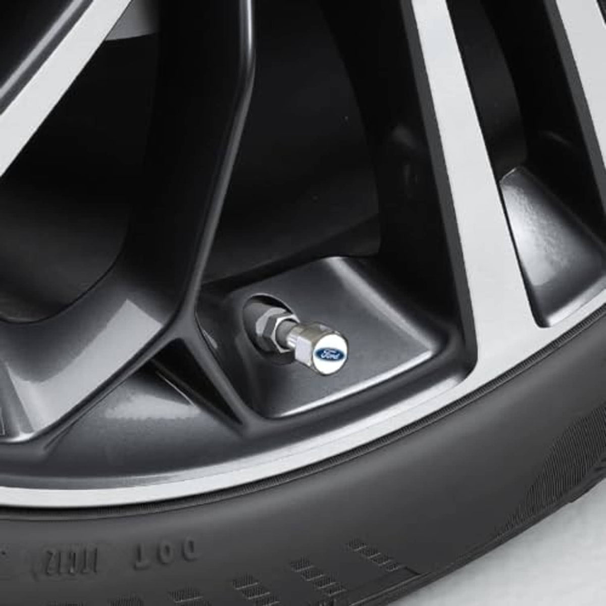 Installed chrome tire valve cap cover with blue Ford logo on the valve stem