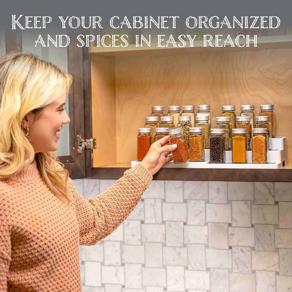 White expandable spice rack on cabinet shelf holding spice jars for easy access.