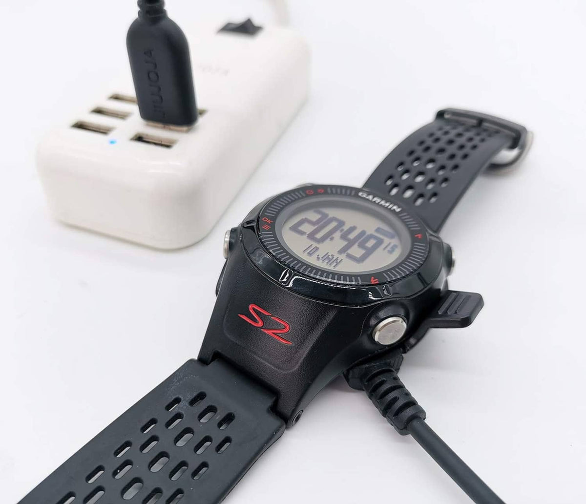 Black watch charging dock with USB cable connected to a Garmin sport watch