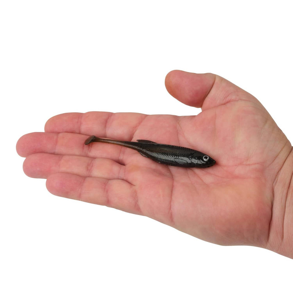 Small dark shad soft plastic fishing lure held in a hand for size