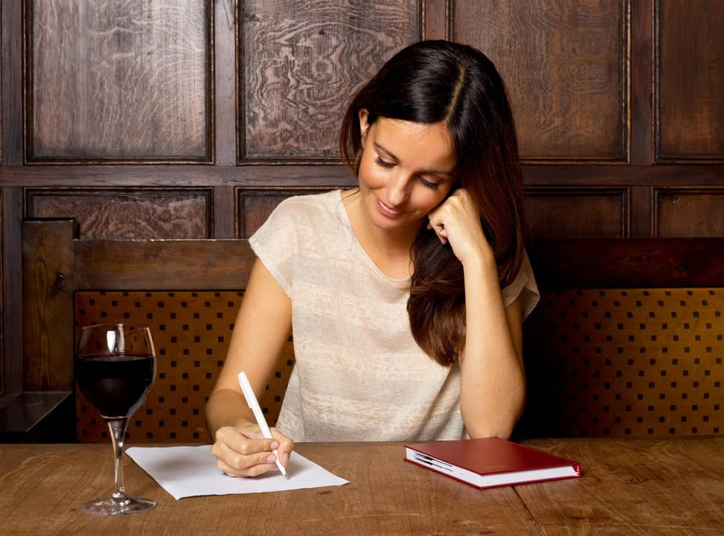 Person writing at a table with mini motivational cards nearby
