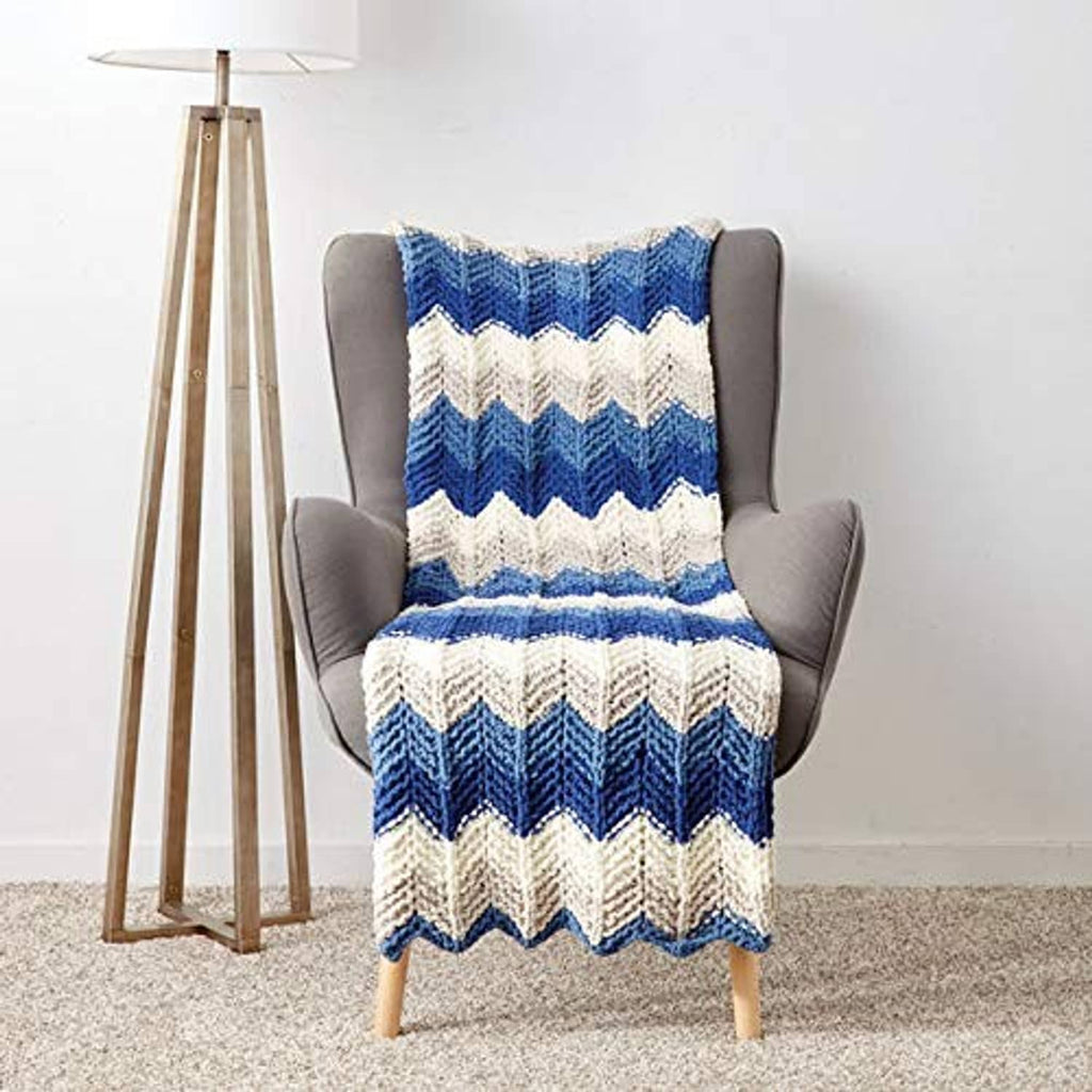 Blue and cream chevron knit throw blanket on gray armchair