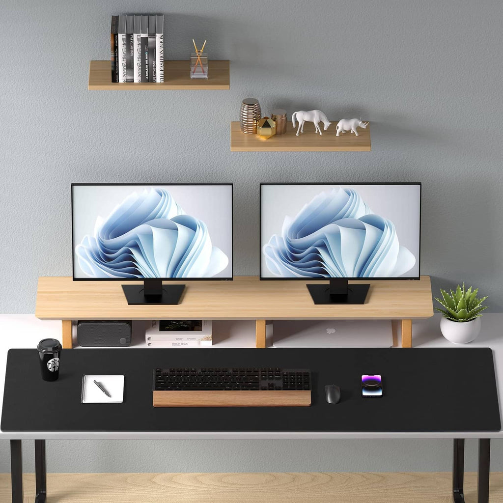 Black desk pad protector on a table with keyboard, laptop, and small desk accessories
