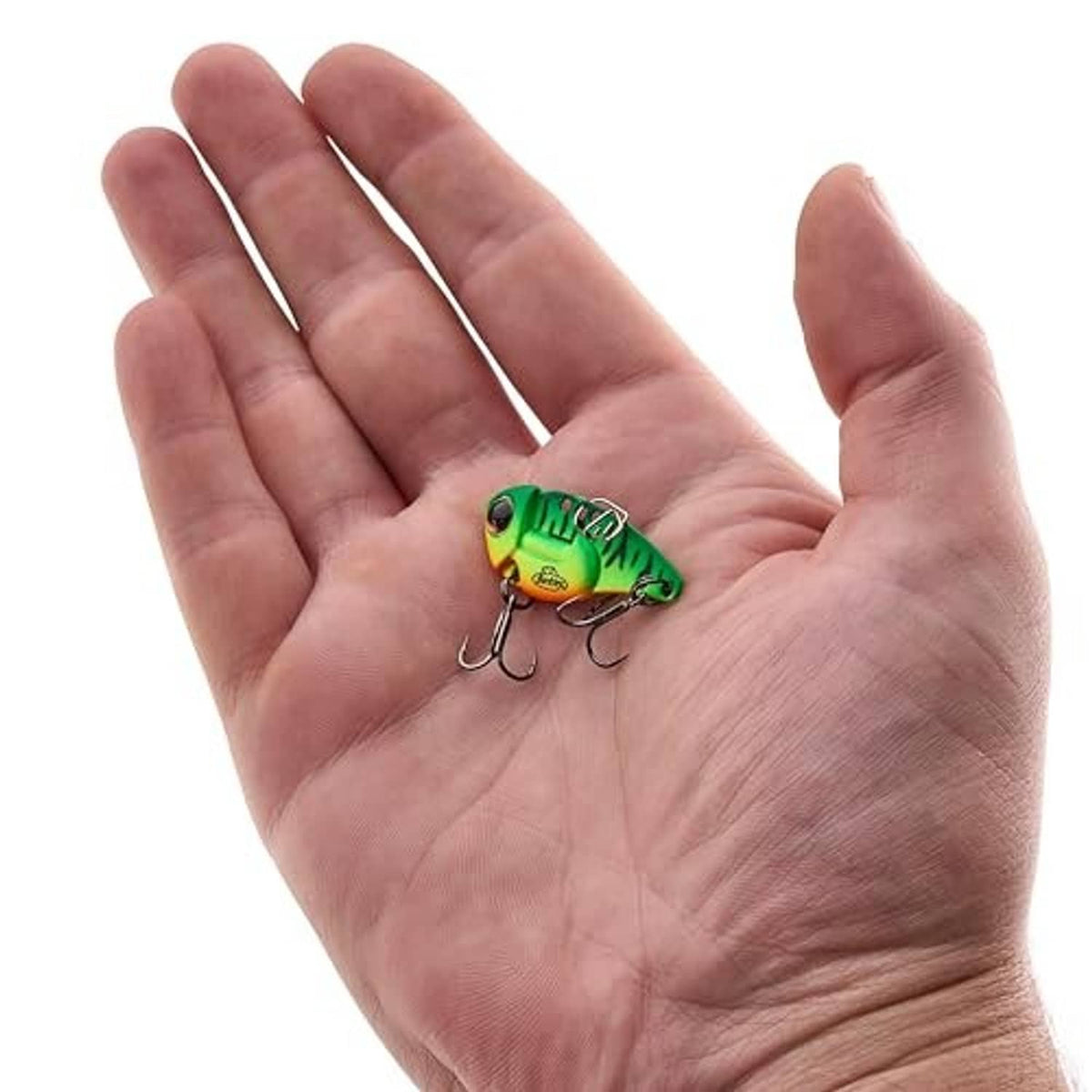 Firetiger blade bait lure in a hand, green and yellow body with treble hooks