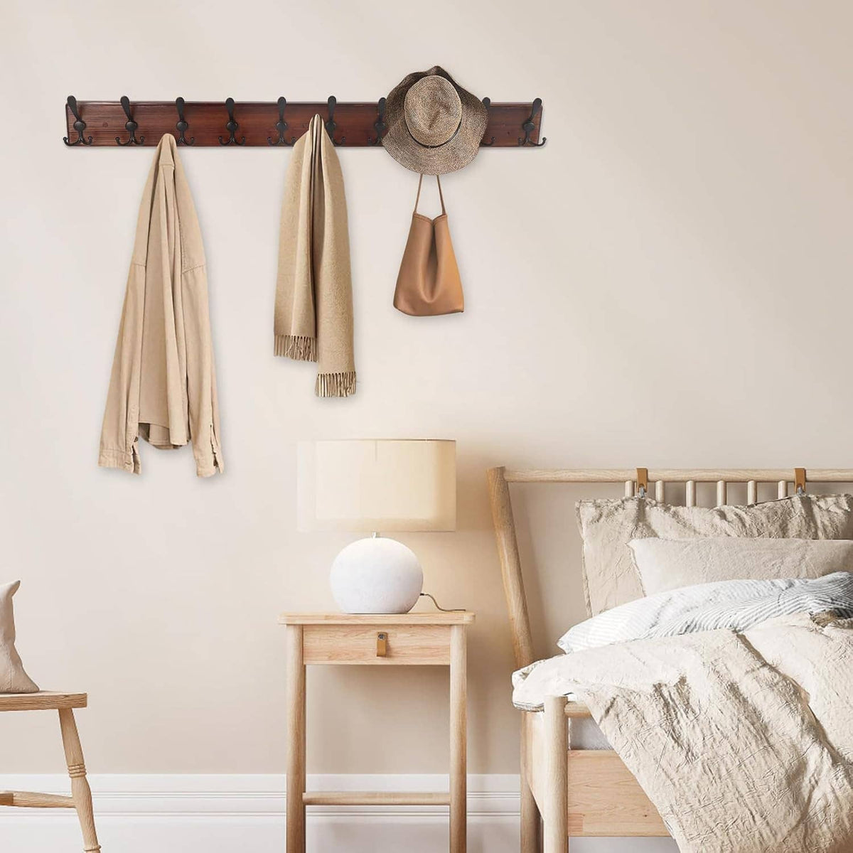 Wall-mounted coat rack with 10 black hooks on dark wood board holding coats and hat