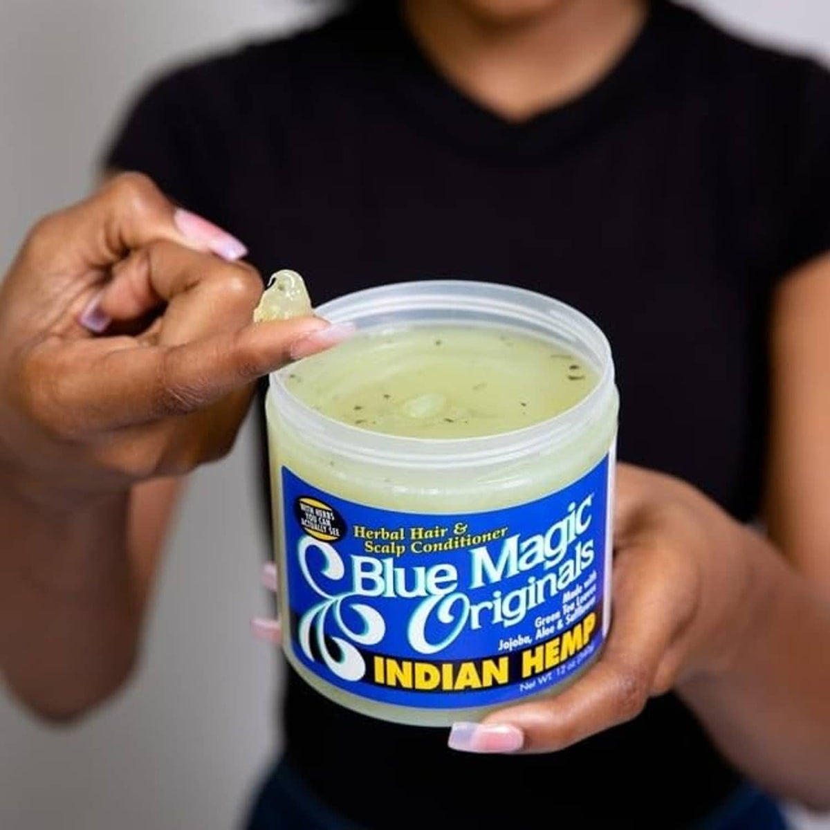 Blue Magic Indian Hemp conditioner jar held with visible pale green cream inside