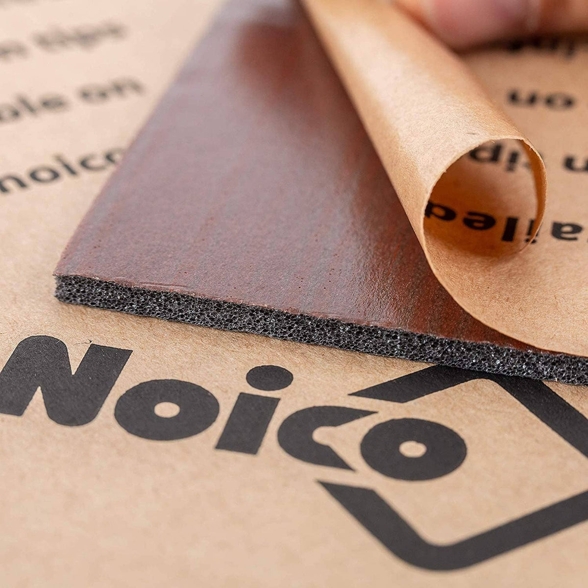 Rolled self-adhesive insulation liner showing dark gray foam edge and brown backing