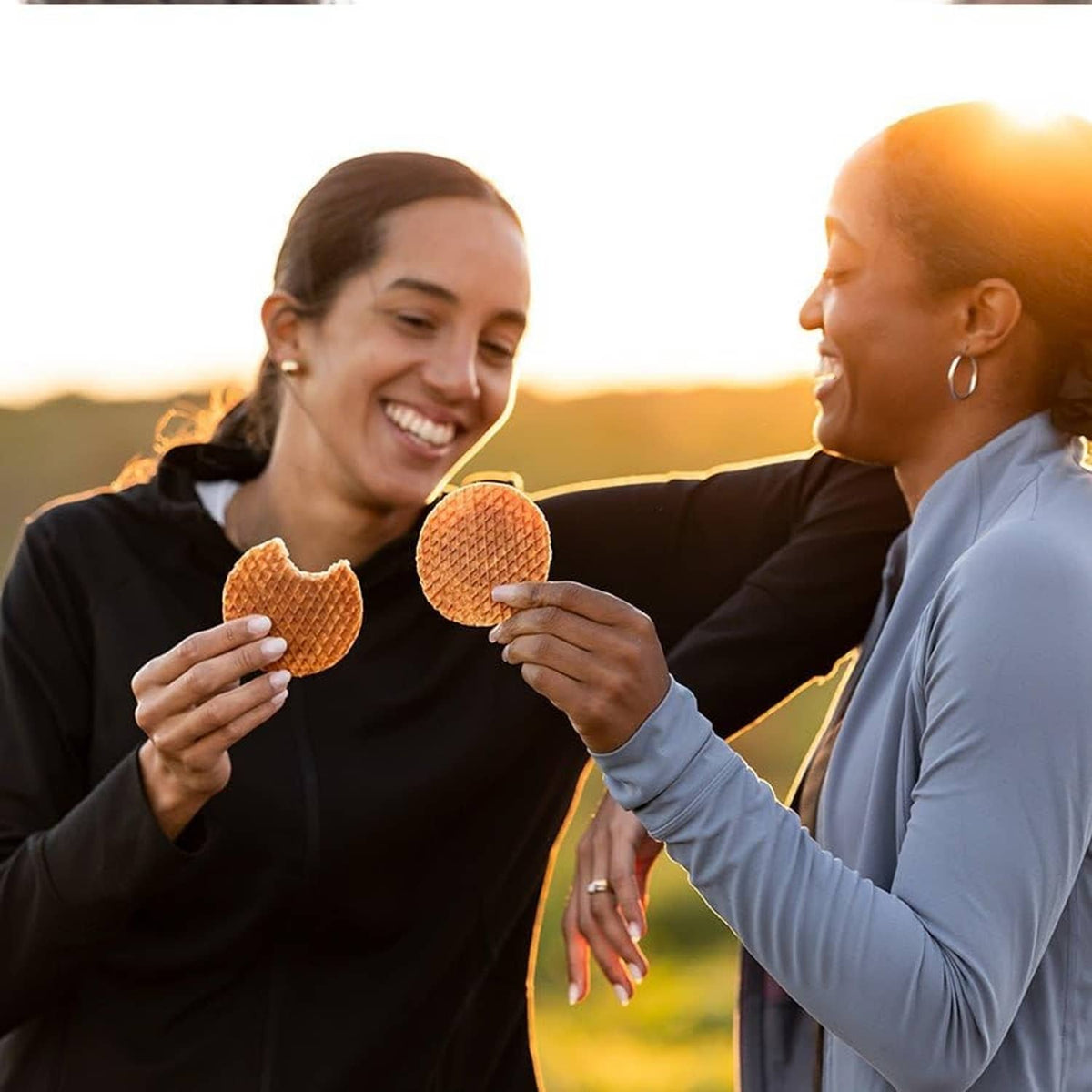 Two people holding Honey Stinger energy chews or wafer snacks outdoors