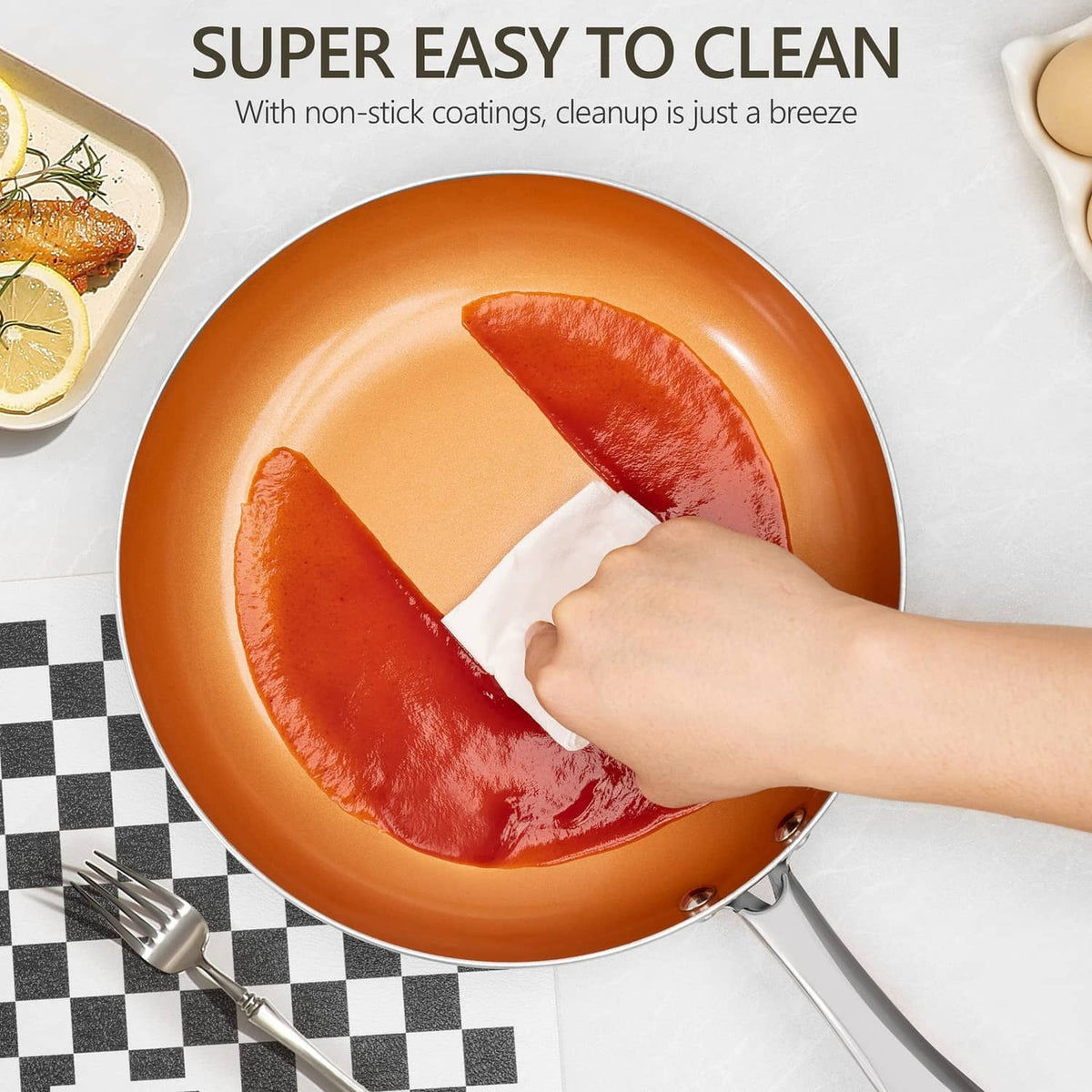 Orange nonstick frying pan interior being cleaned with a cloth, stainless handle