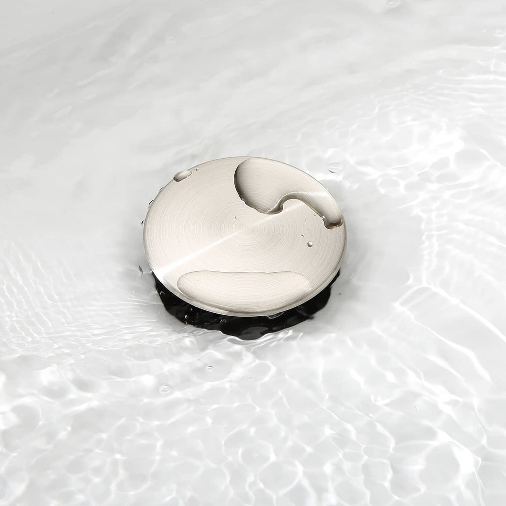 Brushed nickel no-overflow vessel sink drain stopper with black base on sink surface