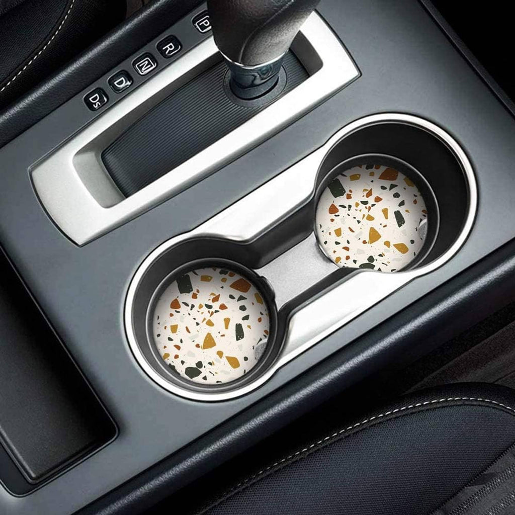 Pair of round speckled ceramic coasters sitting in car cup holders