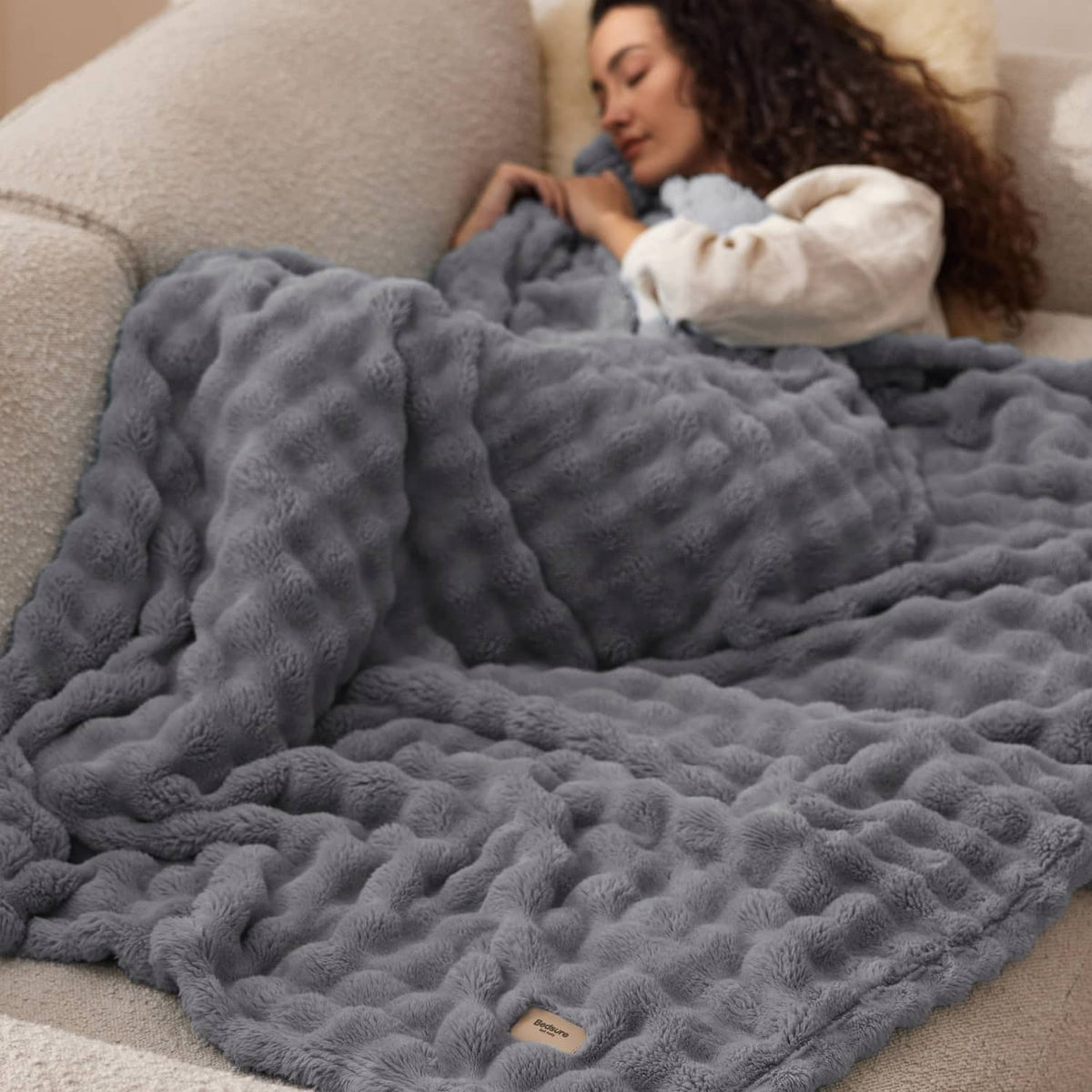 Gray 3D bubble fleece blanket covering a couch, plush raised bubble texture