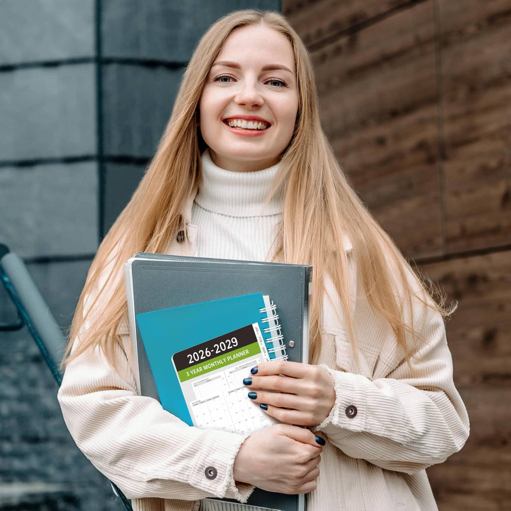 Person holding a black A6 monthly planner refill booklet with tabbed pages inside