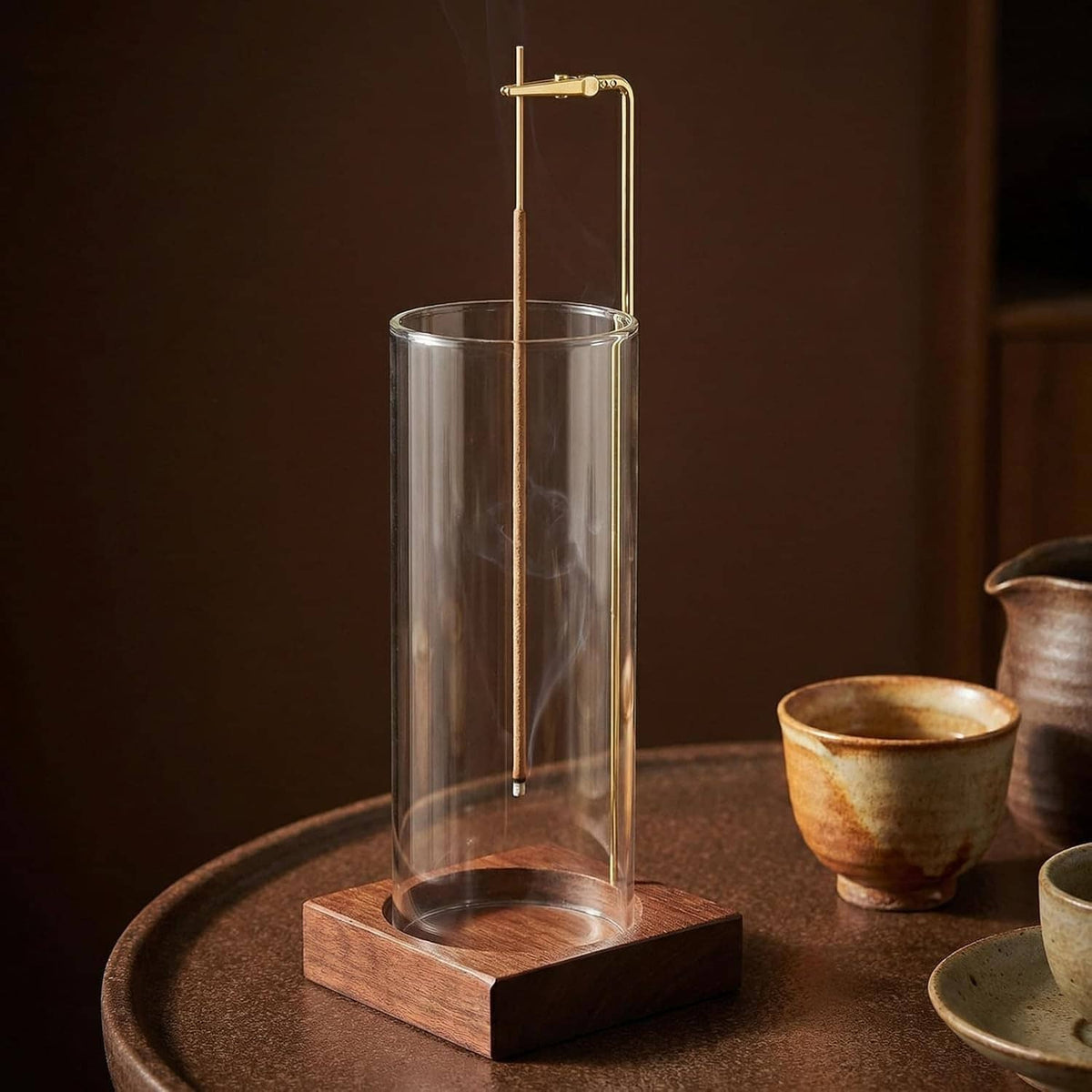 Incense holder with clear glass cylinder and dark wood base on a tabletop