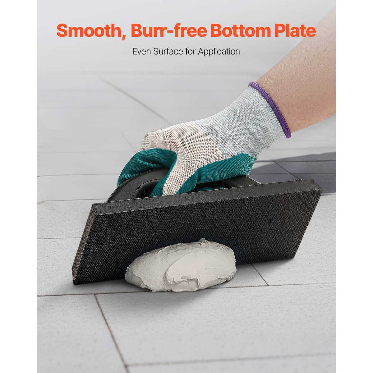 Black grout float with smooth bottom plate; gloved hand spreading grout on tile
