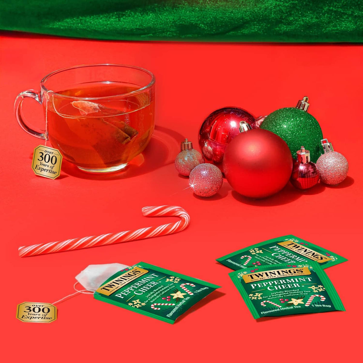 Twinings Peppermint Cheer herbal tea sachets with cup of steeped tea
