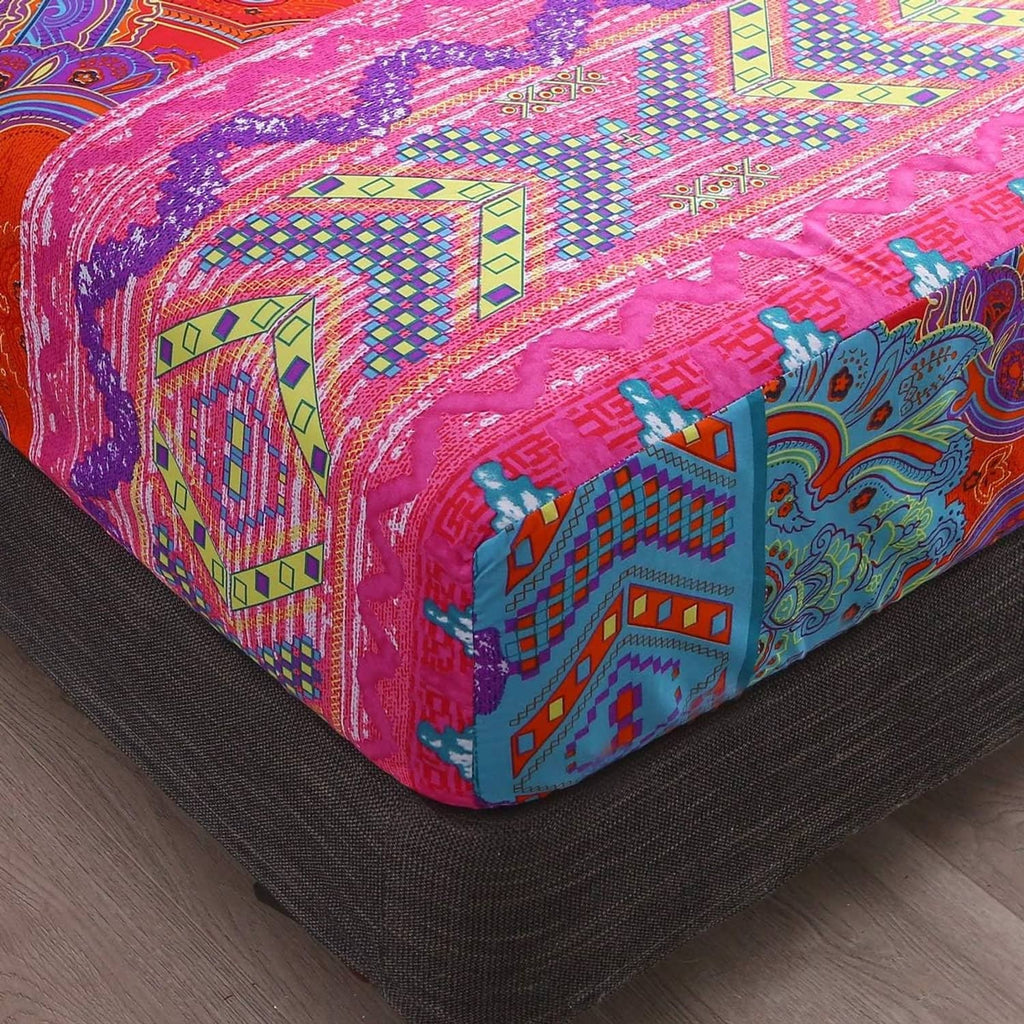 Close-up of colorful boho paisley fitted sheet corners on dark bed base