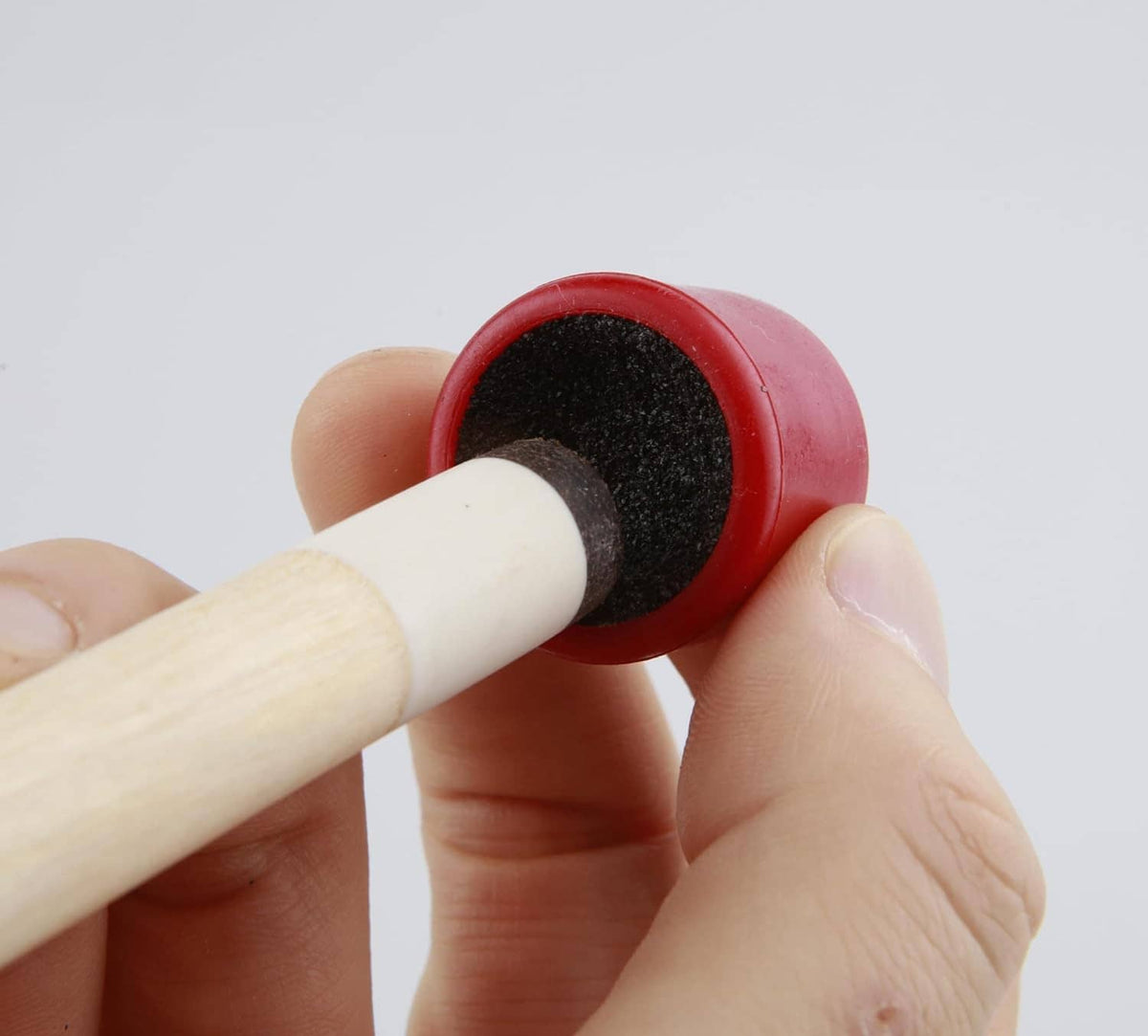 Installing a cue tip: red holder with black pad on a wooden cue