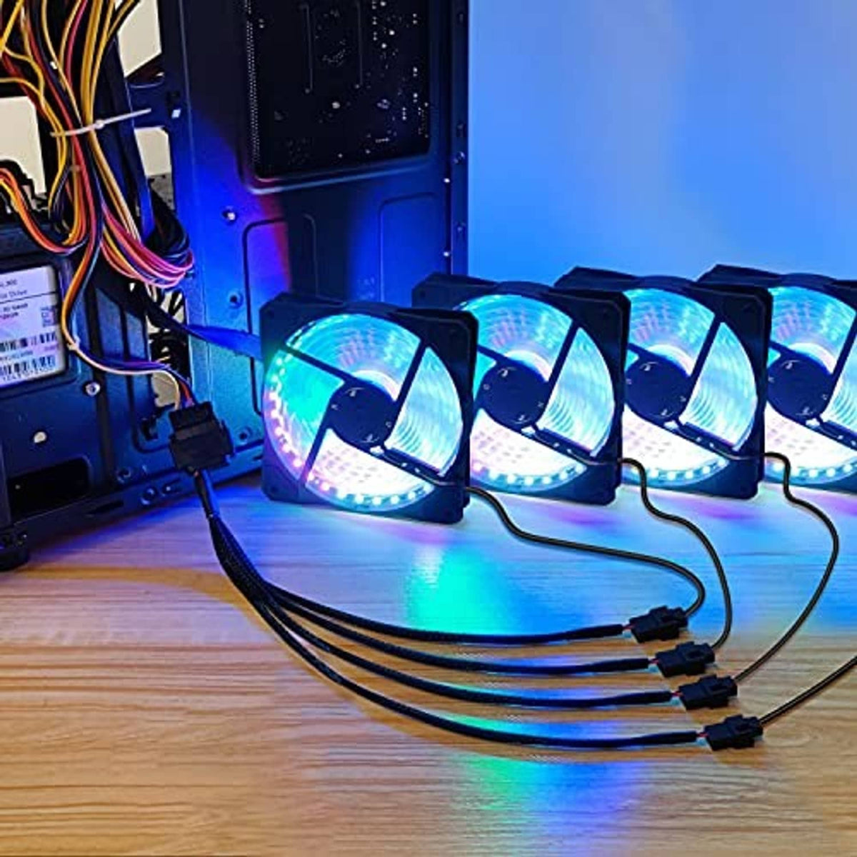 PC cooling fan adapter cable connected to four RGB-style fans on a desktop