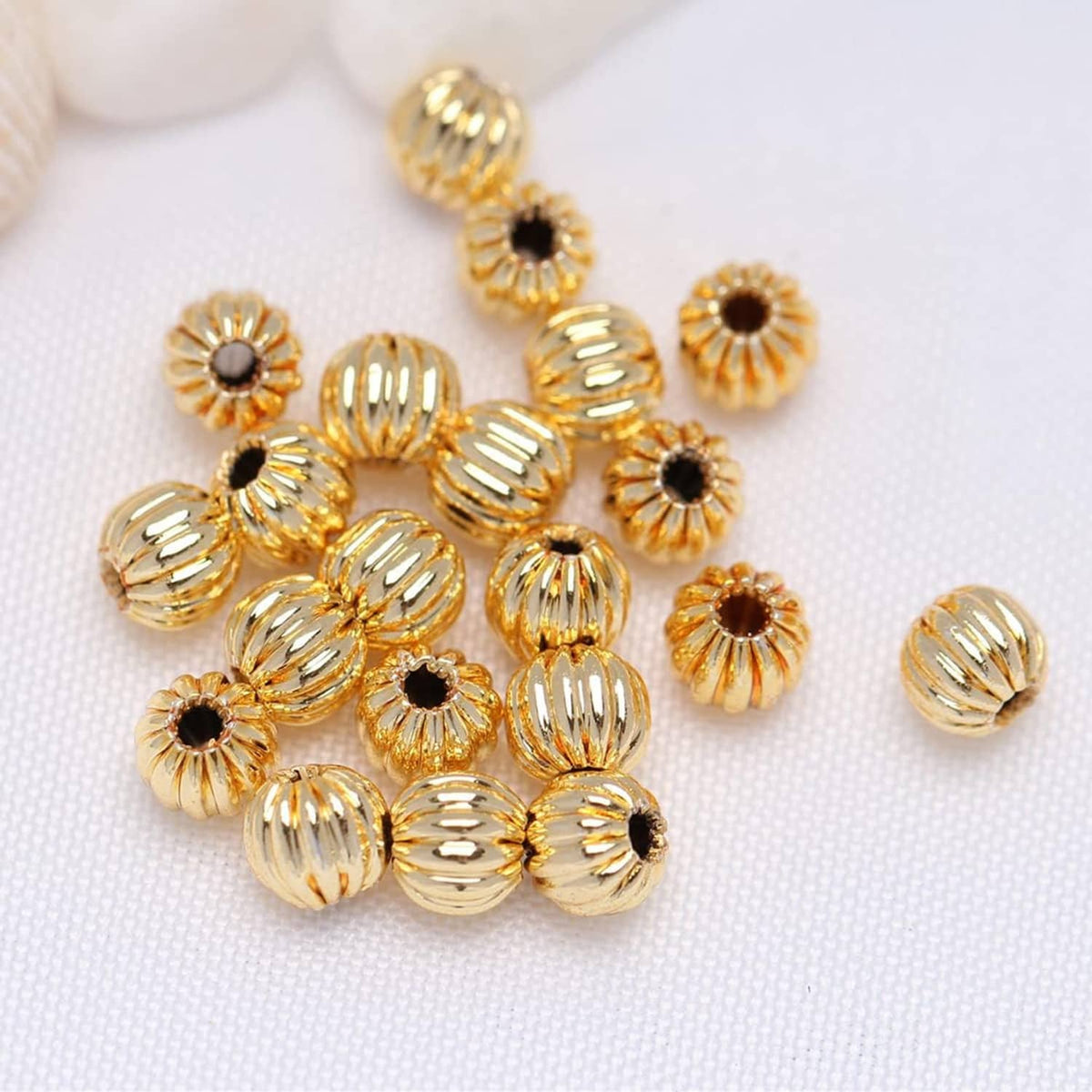 Gold-tone corrugated beads with black center dots and ridged texture