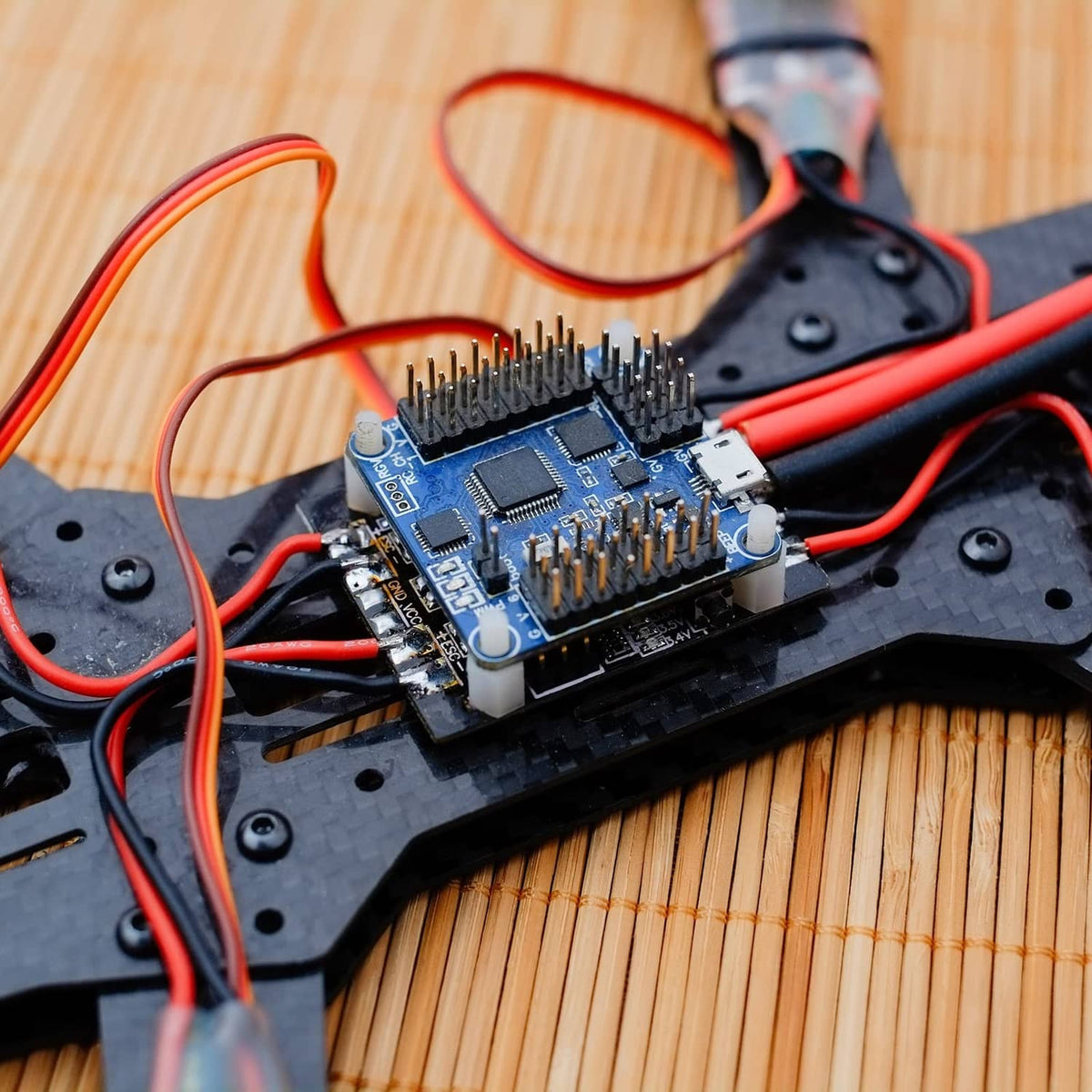 RC drone controller board with red and black wiring on a dark frame
