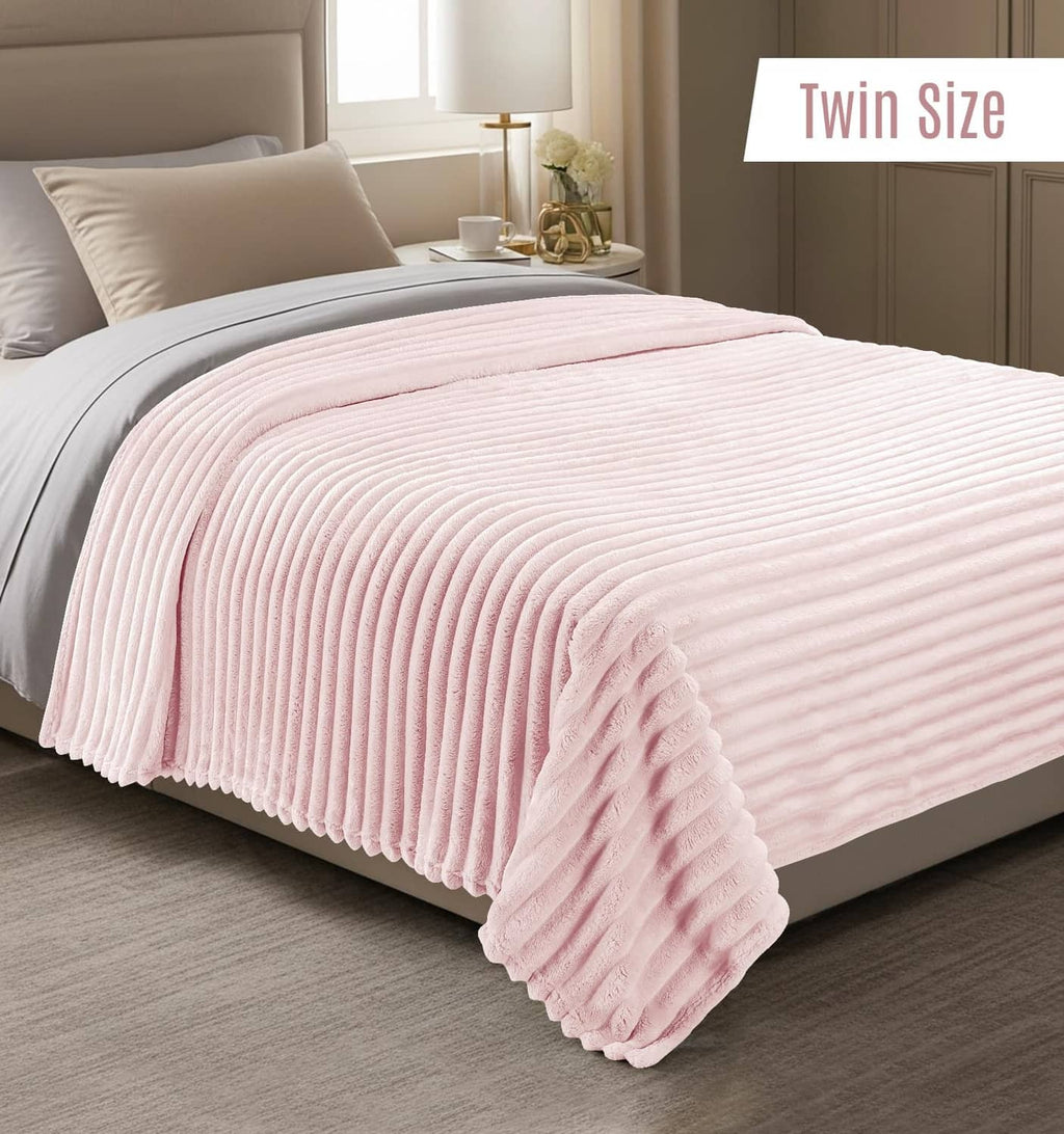 Pink striped fleece blanket on a twin bed, folded over the side