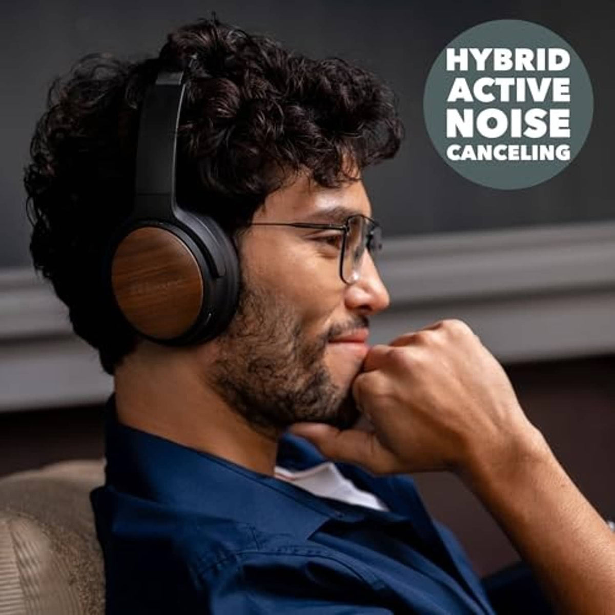Over-ear headphones worn on a person with curly hair, featuring wooden ear cups