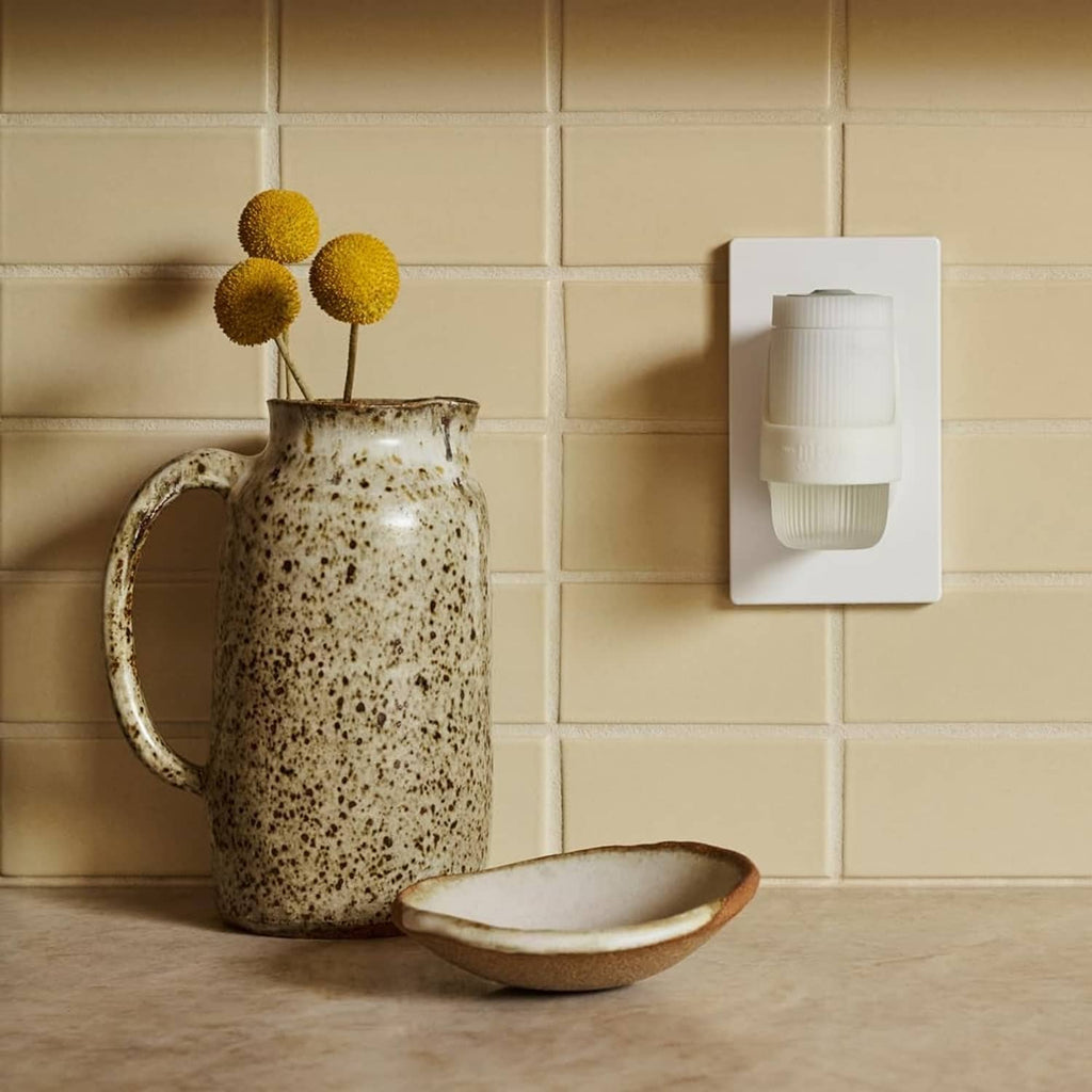 White wall-mounted scent warmer plugged into outlet with scented oil refill