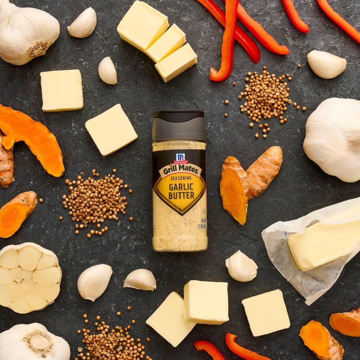 Garlic butter seasoning bottle surrounded by garlic, cheese, peppers, butter, and spices