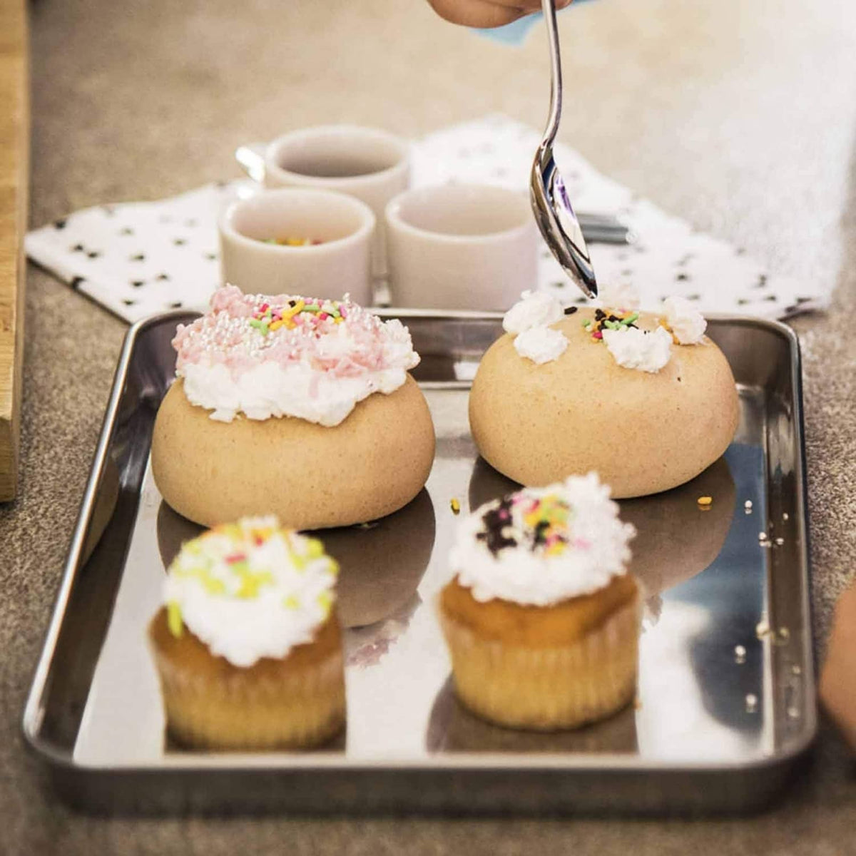 Stainless steel baking tray with frosted cupcakes, rectangular shallow pan