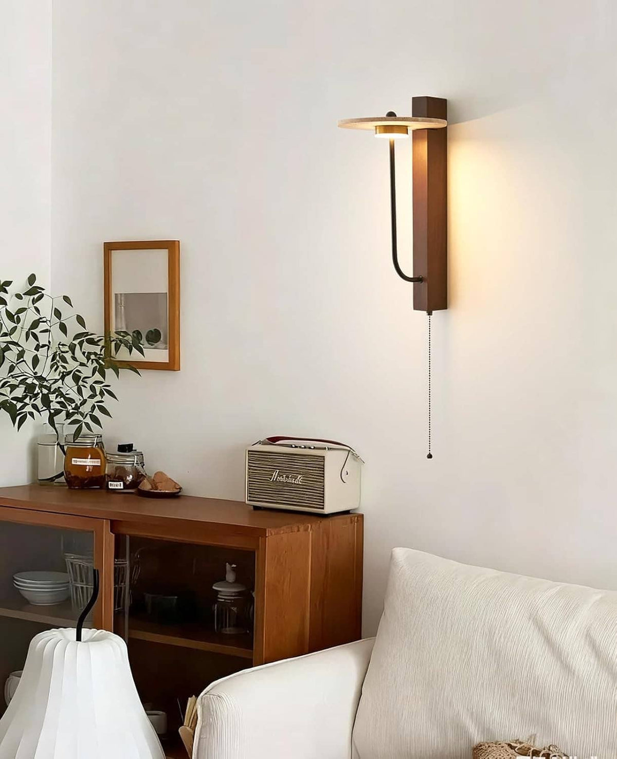 Wall-mounted sconce with round travertine top, dark metal arm, and glowing lamp shade