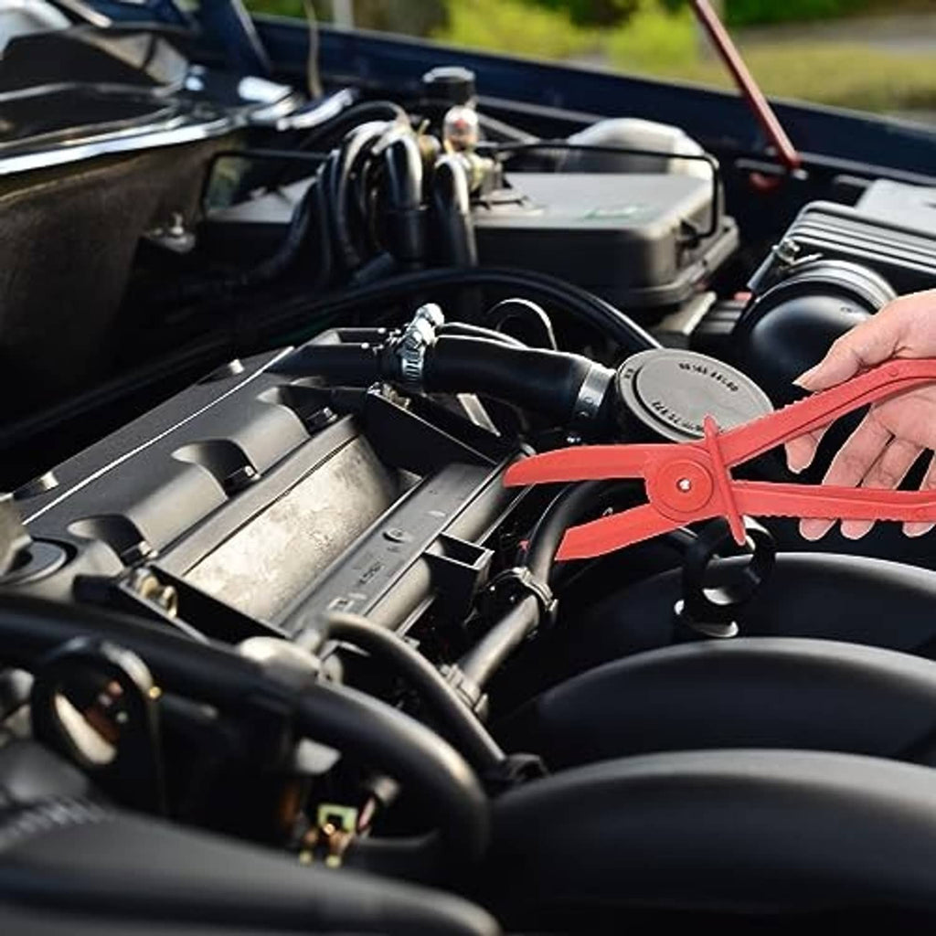 Red plastic hose pinch-off plier clamped on an engine hose by a hand