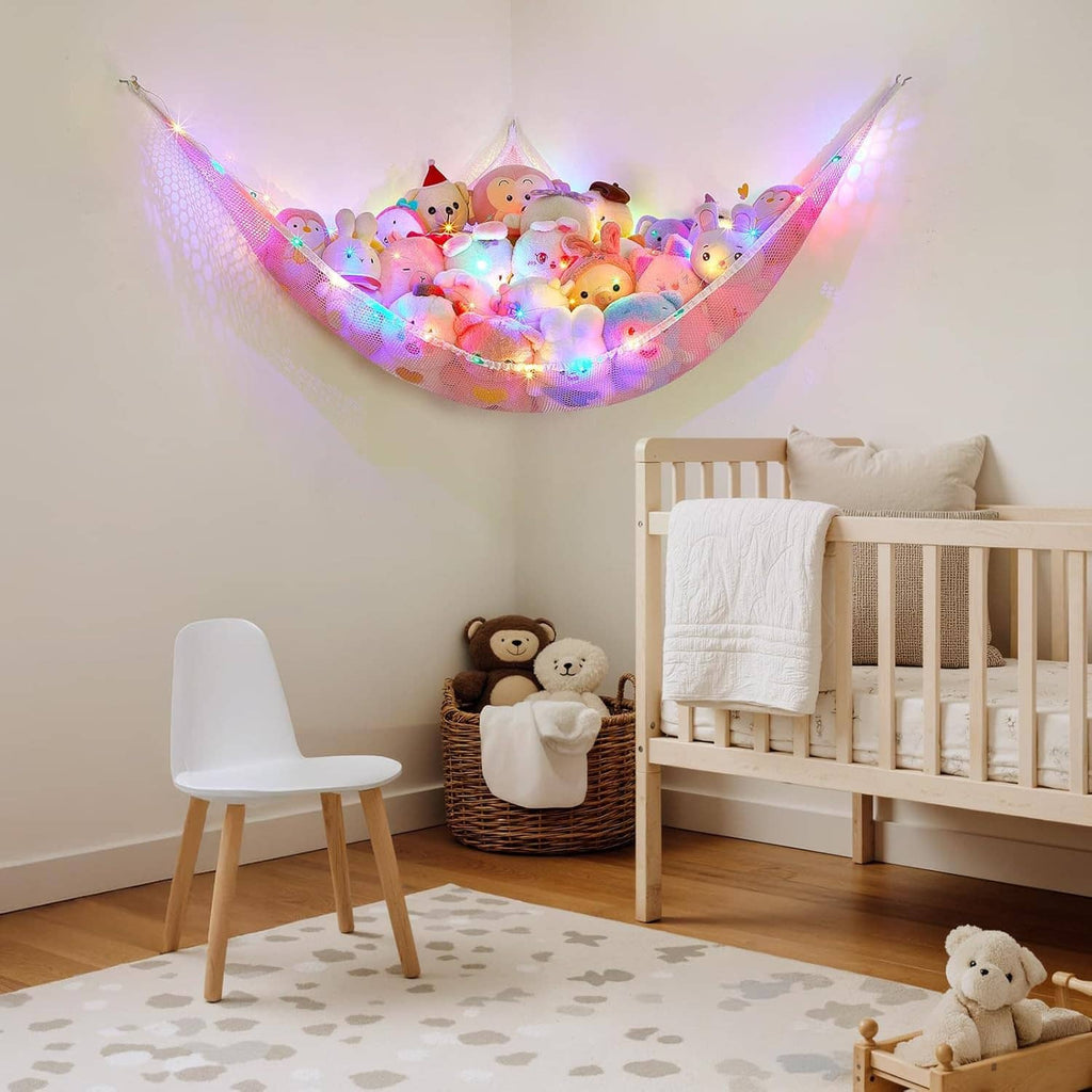 Plush animal hammock net organizer hanging above stacked toys in kids room