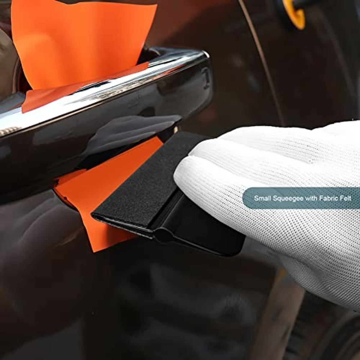 Small squeegee with fabric felt pad smoothing film along a vehicle edge