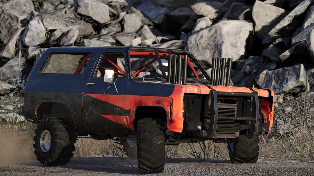 Orange and blue off-road truck climbing rocks with dust in a crash
