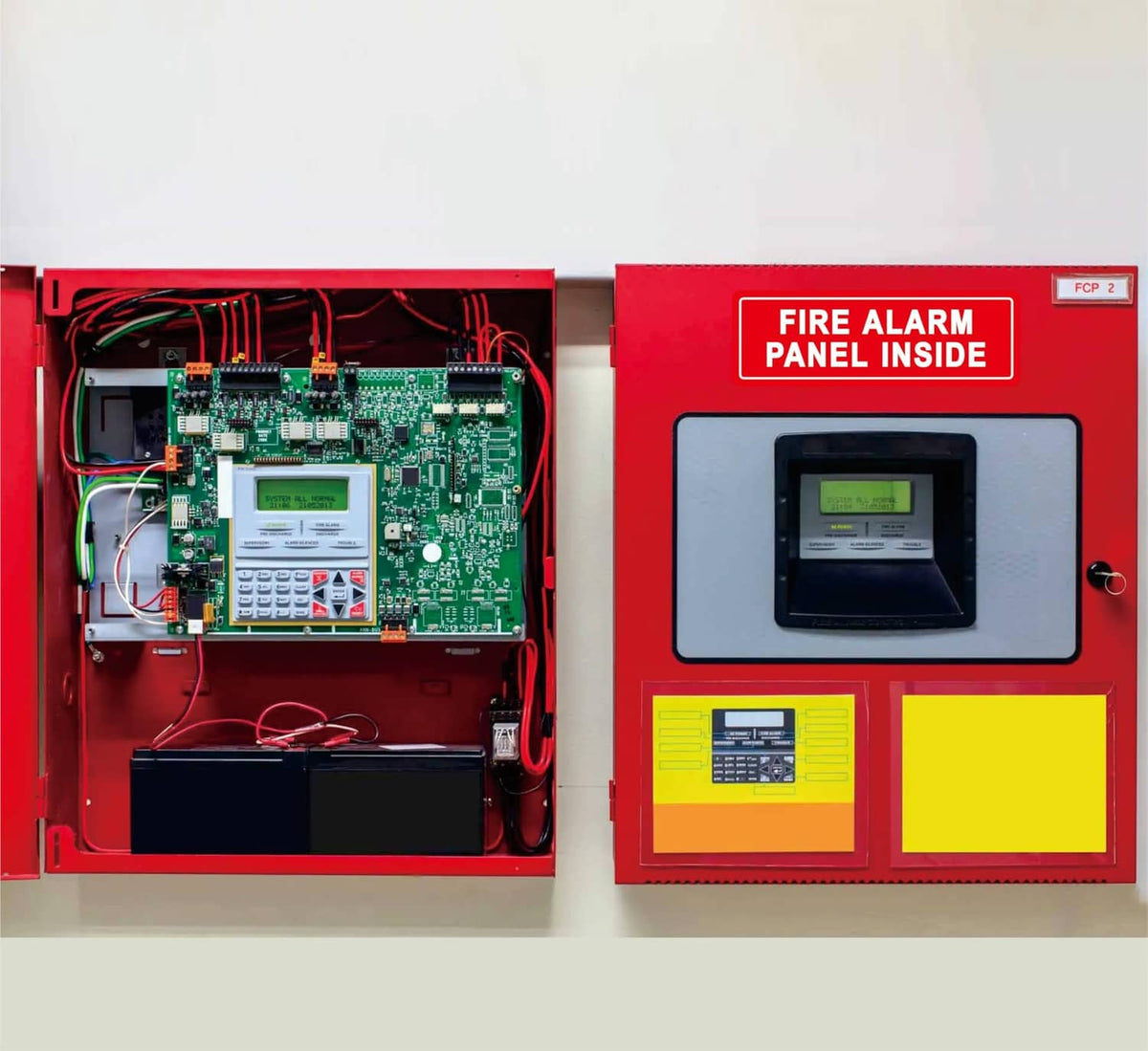 Open red fire alarm panel showing circuit board and control modules, plus label