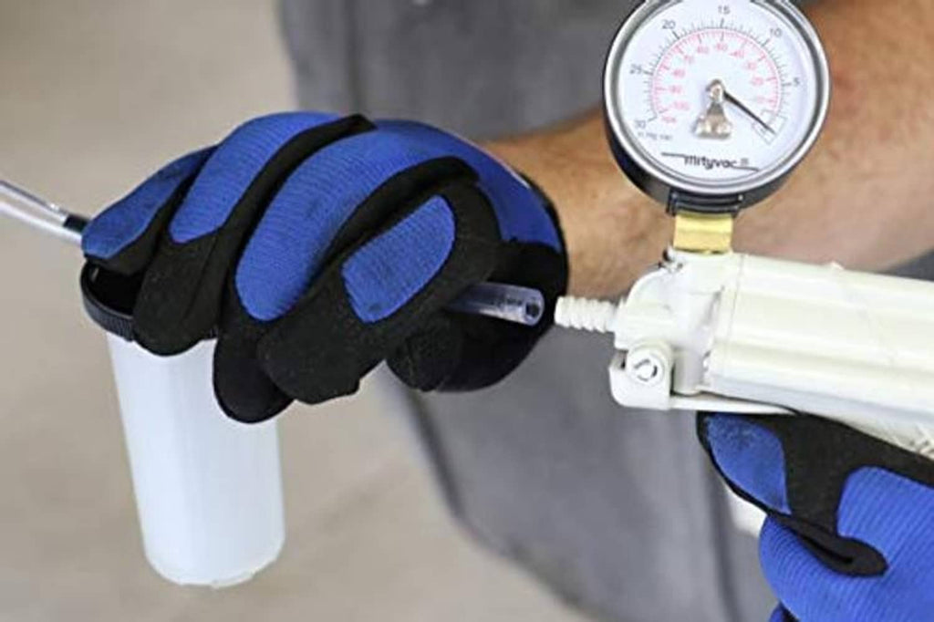 Technician holding a brake bleeder pump with pressure gauge and collection cup