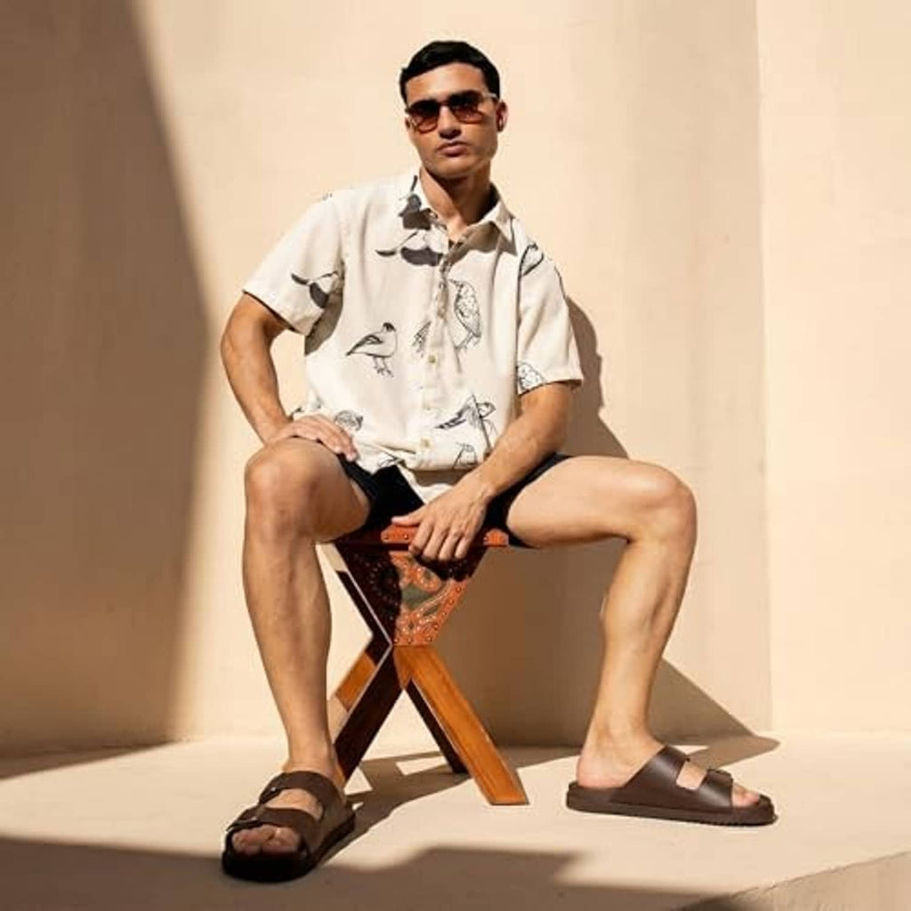 Men's brown slide sandals with adjustable straps, worn with a short-sleeve shirt