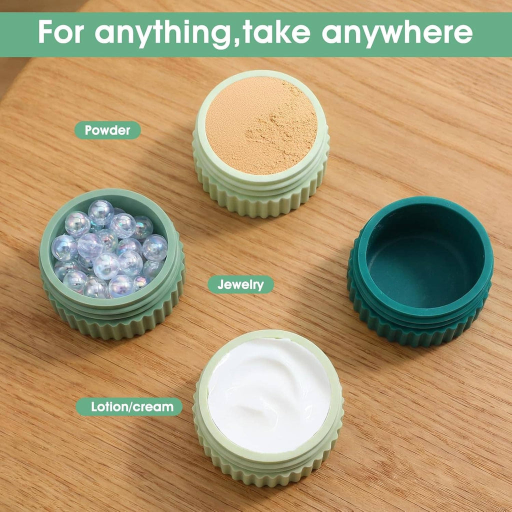 Three small silicone travel jars with ribbed sides, filled with powder, beads, and cream