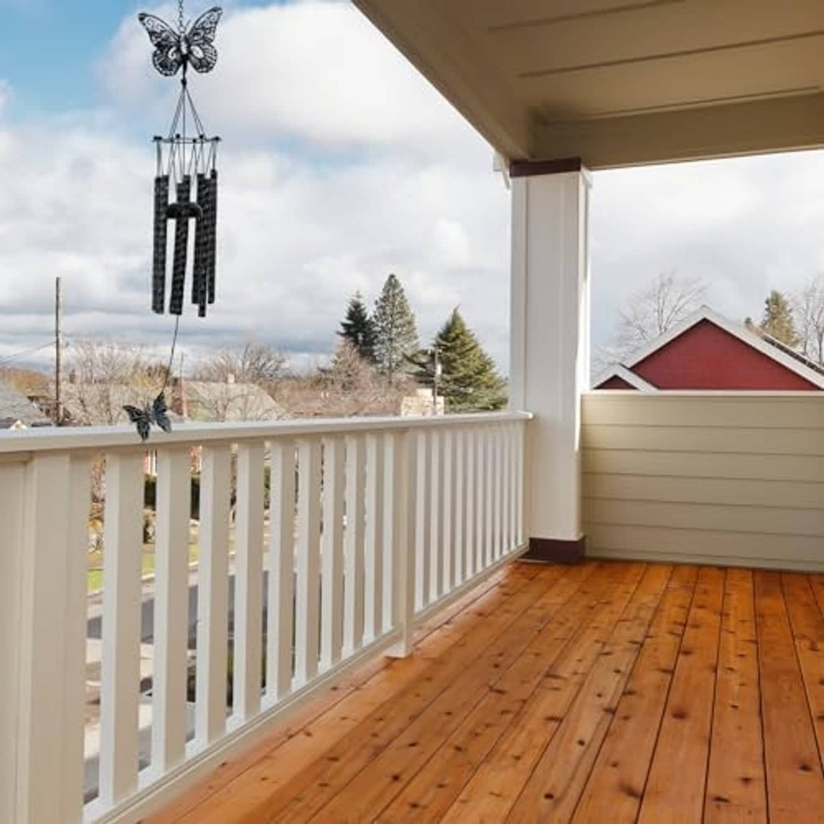 Black butterfly wind chime on porch railing with butterfly topper and hanging bars
