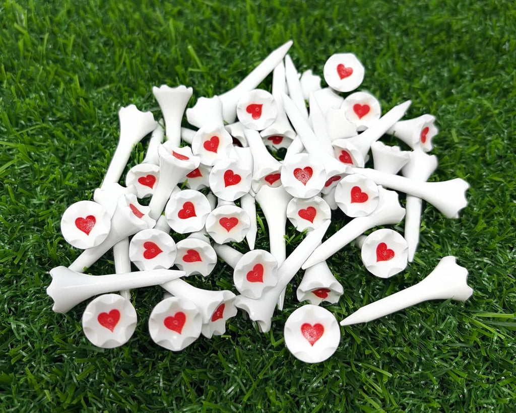 White plastic golf tees with red heart tips on green turf