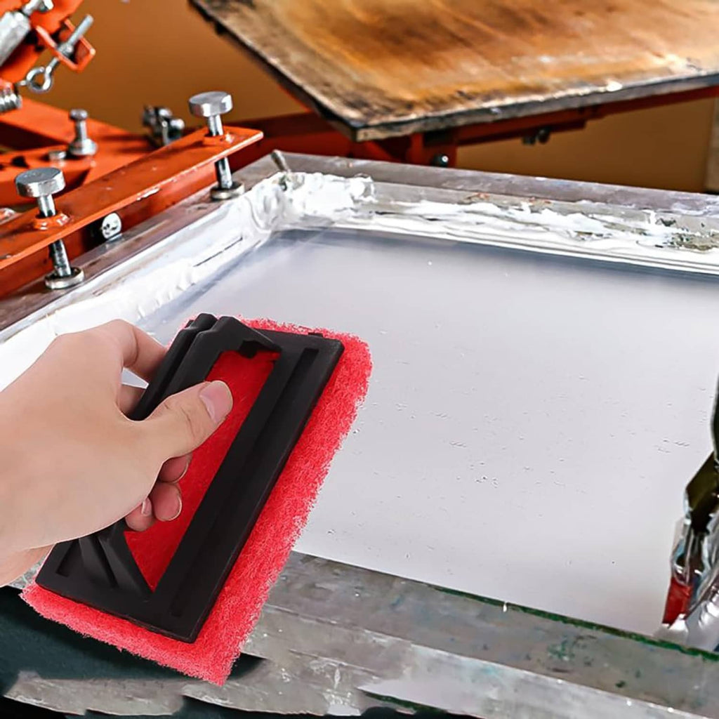 Red sponge scrub brush with black handle used by hand to clean a screen printing frame.