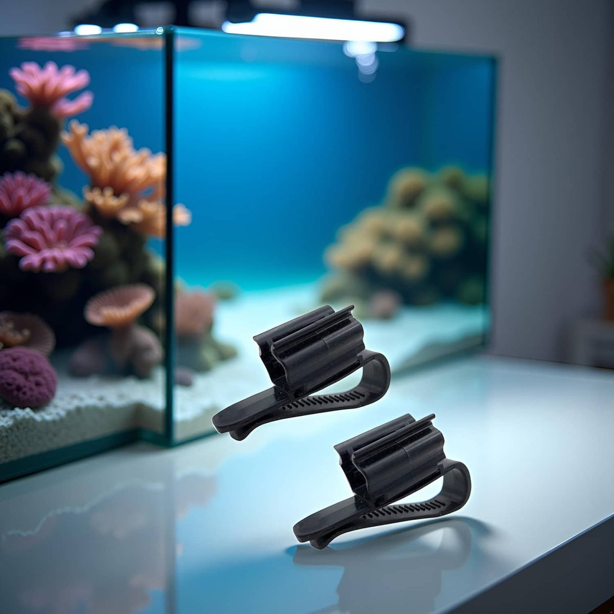 Two black fish tank hose clips with curved clamps and ridged grip pads
