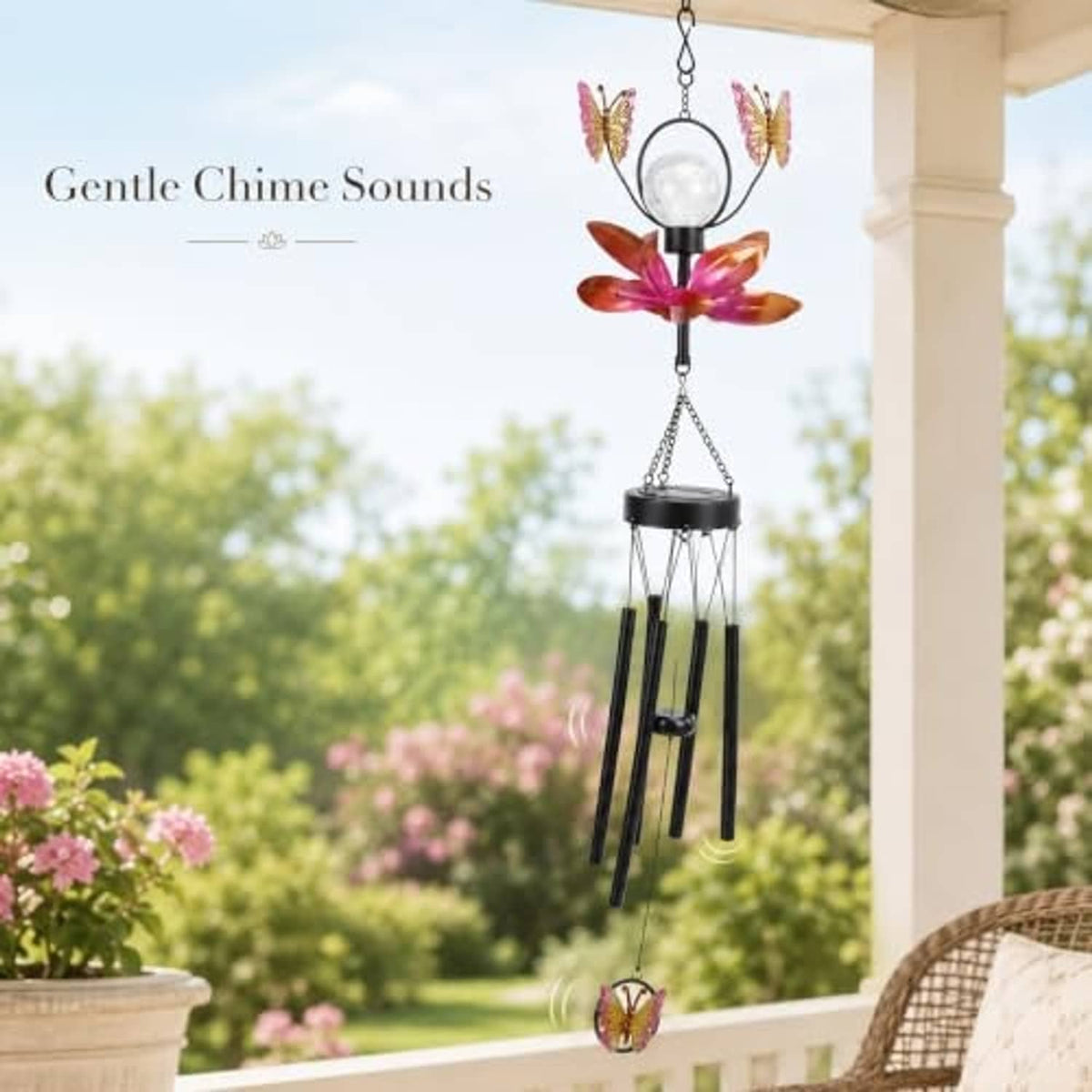 Solar metal wind chime with butterfly and flower spinner hanging on a porch railing