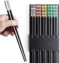 Reusable black chopsticks with clear sleeves, held by hand; organizer display in background