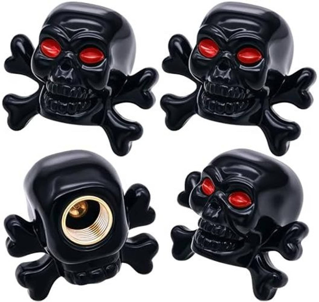 Four black skull tire valve stem caps with red eyes and visible brass valve openings