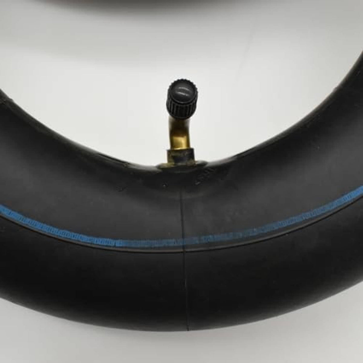 Black inner tube with brass valve and black cap; TR87 bent valve style.