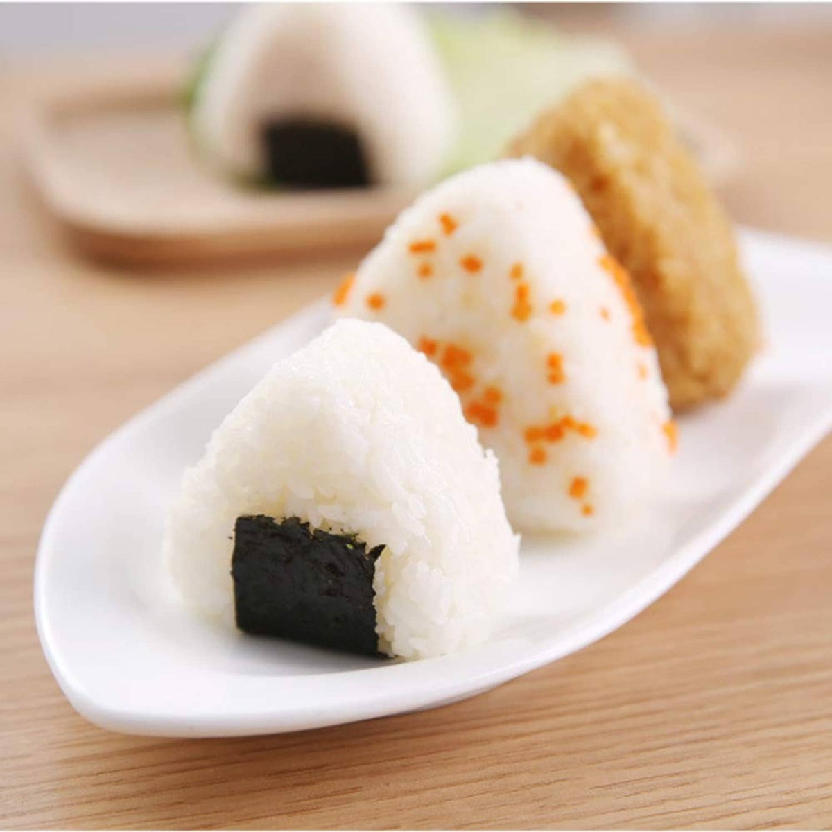 Triangle onigiri on a white plate with nori and mixed filling pieces