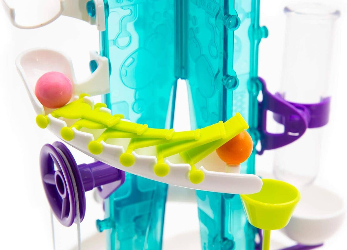 Yellow arm on gumball machine releasing an orange ball toward purple track.